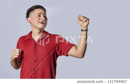 Guy raising hands in victory sign, latin man raising hands in victory on isolated background 122784907