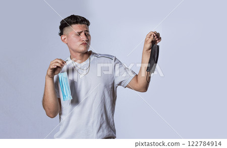 Man deciding to wear surgical mask, Latin man deciding to wear surgical mask on isolated background Man deciding to wear surgical mask, Latin man deciding to wear surgical mask on isolated background 122784914