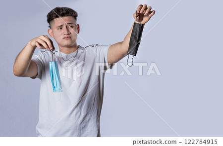 Man deciding to wear surgical mask, Latin man deciding to wear surgical mask on isolated background Man deciding to wear surgical mask, Latin man deciding to wear surgical mask on isolated background 122784915