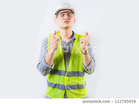 Portrait of young engineer making a wish. Handsome engineer crossing fingers making a wish 122785059