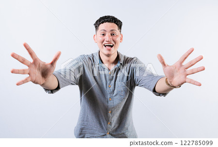 Happy young latin man welcoming with open arms isolated. Hospitable people opening arms to the camera. Smiling man asking for a hug Happy young latin man welcoming with open arms isolated. Hospitable people opening arms to the camera. Smiling man asking for a hug 122785099