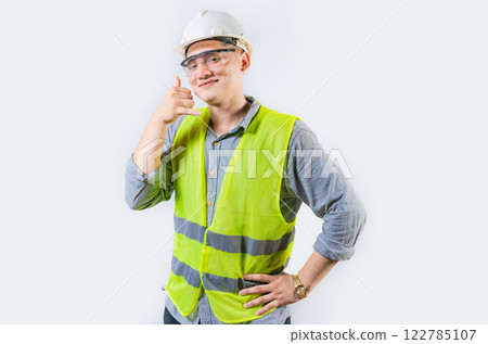 Portrait of young engineer making call gesture isolated. Handsome engineer making call gesture with fingers 122785107