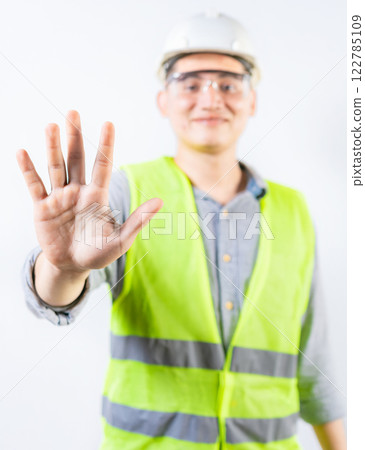 Young engineer counting number five isolated. Smiling engineer showing number five with hand isolated 122785109