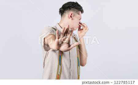 Confused unhappy man grabbing nose with fingers and stretching hand out feeling disgusted, A man with covering his nose 122785117