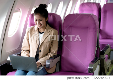 young businesswoman uses laptop while flying airplane for work 122785825