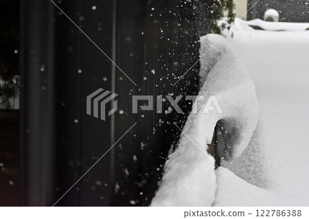 Snow piled up on a block wall, falling snow 122786388