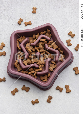 Dry dog food in bowl slowing eating process for overweight dogs Dry dog food in bowl slowing eating process for overweight dogs 122786435