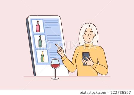 Woman looks through wine menu on phone, choosing drink and standing at bar counter with wineglass 122786597