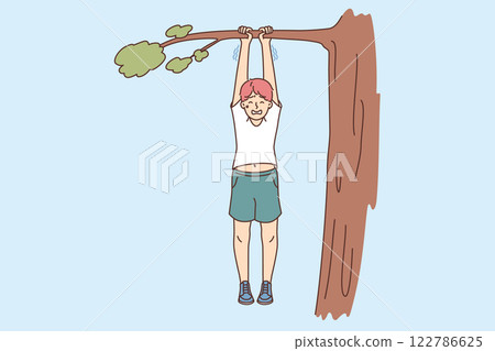 Boy risks falling from tree, hangs on branch and holds on with all strength due to carelessness 122786625