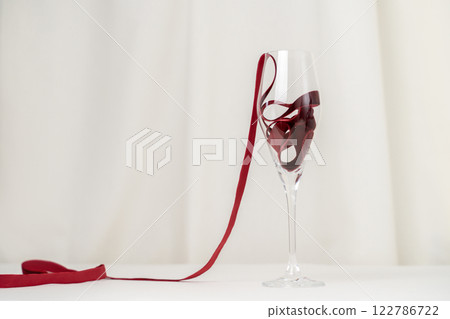 Minimalist Wine Glass and Red Velvet Ribbon on cream Background 122786722