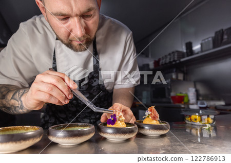 Professional chef garnishing small appetizers Professional chef garnishing small appetizers 122786913