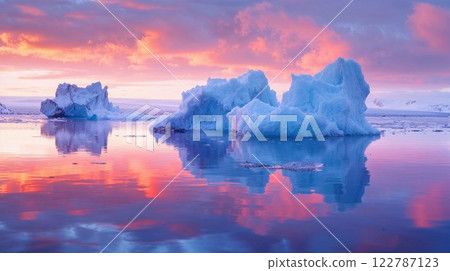 Majestic blue icebergs float peacefully on a still Arctic ocean, reflecting the breathtaking hues of a fiery pink and orange sunset, creating a surreal and mesmerizing natural scene 122787123