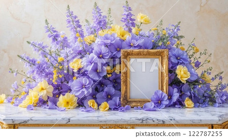Vibrant bouquet of purple and yellow flowers beautifully arranged around a vintage golden frame on a marble table, exuding elegance and charm 122787255