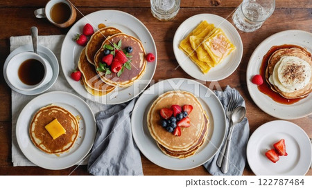 breakfast table featuring a variety of pancake dishes topped with fresh berries, syrup, and butter, served with coffee, creating the ultimate cozy morning feast breakfast table featuring a variety of pancake dishes topped with fresh berries, syrup, and butter, served with coffee, creating the ultimate cozy morning feast 122787484