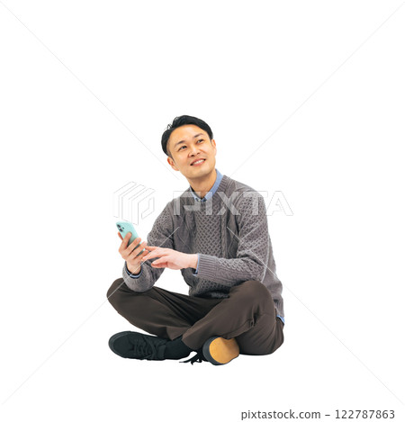 A middle-aged man in casual wear sitting and using a smartphone. A transparent full-body photo PNG precisely cut by hand 122787863