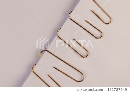 large sized copper paper clips lie on white blank paper 122787949