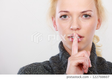 Woman holding finger close to lips, silence Woman holding finger close to lips, silence 122788607