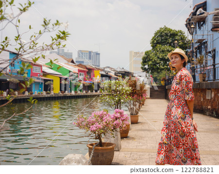 woman in dress and hat exploring vibrant streets of Malacca, Malaysia. 122788821