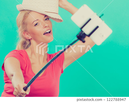 Woman taking picture of herself with phone on stick Woman taking picture of herself with phone on stick 122788947