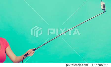 Woman hand holding phone on selfie stick 122788956