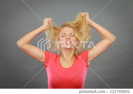 Frustrated woman holding her damaged blonde hair 122789002