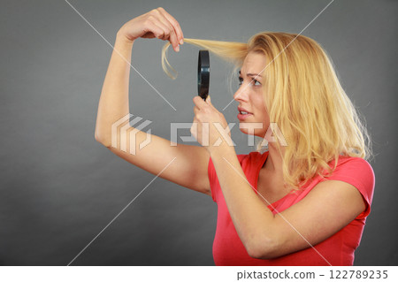 Woman looking at hair through magnifying glass 122789235
