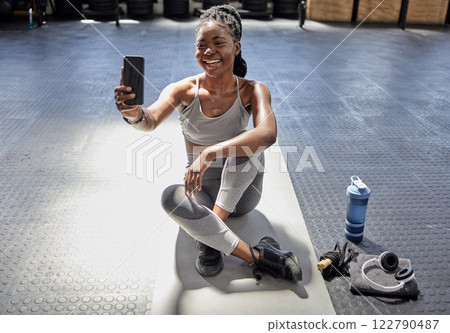 Woman taking selfie with phone at gym, talking on video call with smartphone before workout for fitness training and happy with conversation on tech before exercise. Athlete in conversation at club Woman taking selfie with phone at gym, talking on video call with smartphone before workout for fitness training and happy with conversation on tech before exercise. Athlete in conversation at club 122790487