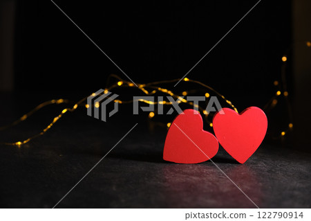 Two hearts side by side on a dark background and garlands Two hearts side by side on a dark background and garlands 122790914