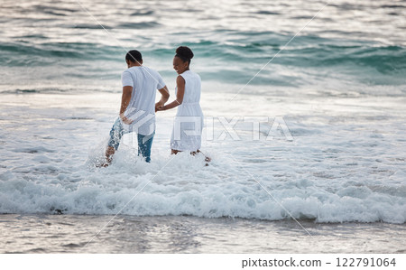 Love, beach and travel couple happy walking in water, by the ocean or waves together bonding on holiday or vacation. Man and woman holding hands during honeymoon smiling in the sea. Love, beach and travel couple happy walking in water, by the ocean or waves together bonding on holiday or vacation. Man and woman holding hands during honeymoon smiling in the sea. 122791064