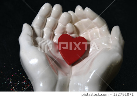 In the palms of white hands there is a red heart 122791071