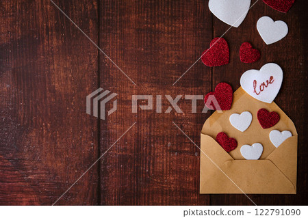 An envelope with an envelope and hearts on a wooden background 122791090