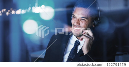 Customer service, call center or telemarketing agent talking and helping client while working late in an office. Happy male helpdesk worker having a conversation with an international partner online 122791359
