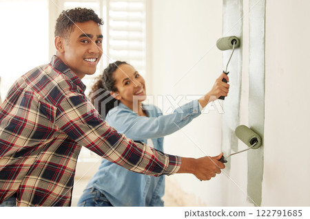 Happy couple painting for renovation with a brush in the living room at home. Portrait of a creative man and woman with a smile add paint on wall in the lounge for home improvement and maintenance Happy couple painting for renovation with a brush in the living room at home. Portrait of a creative man and woman with a smile add paint on wall in the lounge for home improvement and maintenance 122791685