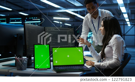 Engineer working with mockup laptop and tablet in data center used for managing gear energy consumption. Employee using green screen devices in workplace used for automation in server farm, camera B 122791823