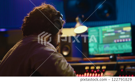 Talented guitarist doing live performance in professional studio, recording new tracks on mixing console amplifier. Young artist musician performing new songs, create music. Camera A. 122791829