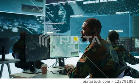 Soldiers in a state of the art military control room collaborate on data analysis, intelligence gathering, and mission planning. Ensure effectiveness and security of military operations. Camera B. 122791898