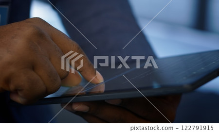 Software developer doing yearly maintenance using tablet to prolong data center equipment life span. Extreme close up of worker in server hub monitoring server infrastructure using device, camera A 122791915