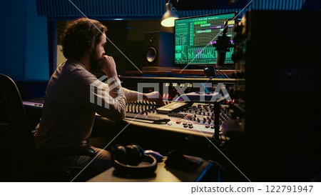 Music producer fixing coiled cable inside amplifier or audio compressor, prepares control room technical equipment for a recording session. Sound engineer works on producing tracks. Camera B. 122791947