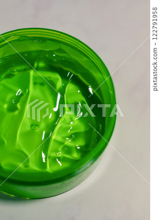 Aloe vera gel close-up, in bright green container on a white surface. High quality photo 122791958