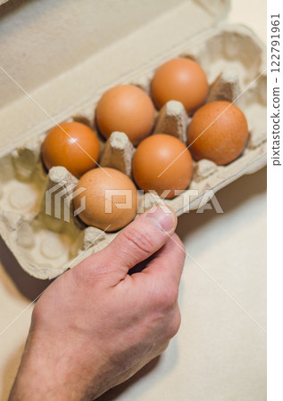 Hand holding carton of fresh eggs, natural food, healthy breakfast ingredient. High quality photo 122791961