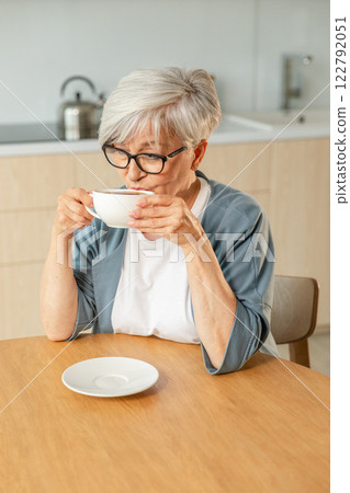 Good morning. Comfort relaxed senior old elderly woman grandmother drinking hot beverage tea coffee in kitchen at home. Mature woman resting enjoy calm morning at modern home alone. Pension concept 122792051