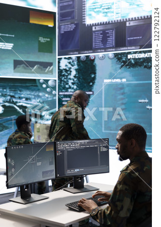 Soldier in a secure environment ensuring data analysis and processing, gathering intelligence for strategic planning to ensure a successful defense mission. Secret service activity. 122792124