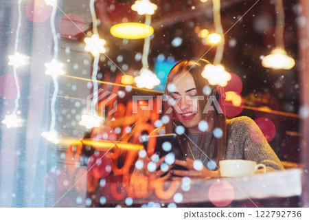 Young beautiful woman sitting in cafe, drinking coffee. Model listening to music. Christmas, Happy new year, Valentines day, winter holidays concept 122792736