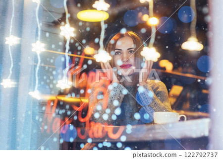 Young beautiful woman sitting in cafe, drinking coffee. Model listening to music. Christmas, Happy new year, Valentines day, winter holidays concept 122792737