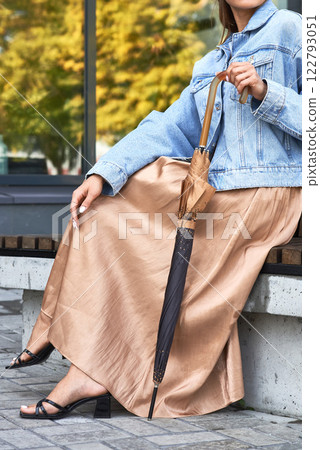Elegant woman with umbrella sitting on bench, wearing jean jacket, stylish fashion, outdoor autumn scene, casual wear concept Elegant woman with umbrella sitting on bench, wearing jean jacket, stylish fashion, outdoor autumn scene, casual wear concept 122793051