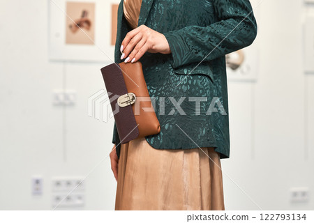 Elegantly dressed woman holding a stylish leather clutch purse in a modern art gallery setting, fashion concept Elegantly dressed woman holding a stylish leather clutch purse in a modern art gallery setting, fashion concept 122793134