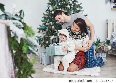 Happy family at christmas in morning opening gifts together near the fir tree. The concept of family happiness and well-being Happy family at christmas in morning opening gifts together near the fir tree. The concept of family happiness and well-being 122793392