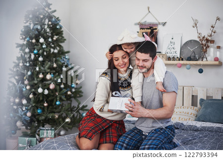 Happy family at christmas in morning opening gifts together near the fir tree. The concept of family happiness and well-being Happy family at christmas in morning opening gifts together near the fir tree. The concept of family happiness and well-being 122793394