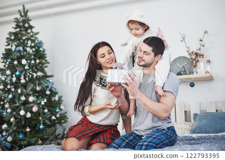 Happy family at christmas in morning opening gifts together near the fir tree. The concept of family happiness and well-being Happy family at christmas in morning opening gifts together near the fir tree. The concept of family happiness and well-being 122793395