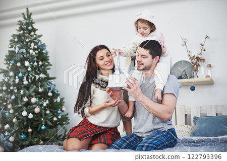 Happy family at christmas in morning opening gifts together near the fir tree. The concept of family happiness and well-being Happy family at christmas in morning opening gifts together near the fir tree. The concept of family happiness and well-being 122793396